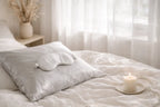 Sleep mask on a pillow with a candle on a nightstand in a bedroom setting